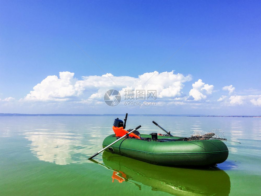 在阳光明媚的天气中在平静的河流中有充气的船橡胶孤单船在阳光阴云的天气中有充的橡皮船图片