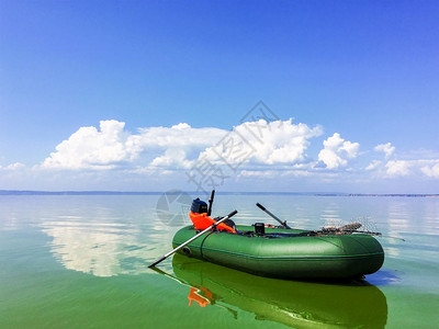 在阳光明媚的天气中在平静的河流中有充气的船橡胶孤单船在阳光阴云的天气中有充的橡皮船图片