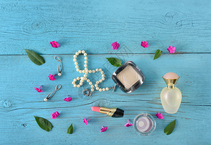 女士的口红珍珠项链粉底和香水放置在木桌上图片