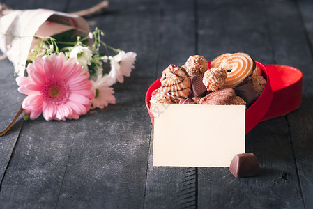 一张空纸贴着一张红盒的贺卡想法上面装满了饼干巧克力和一束鲜花图片