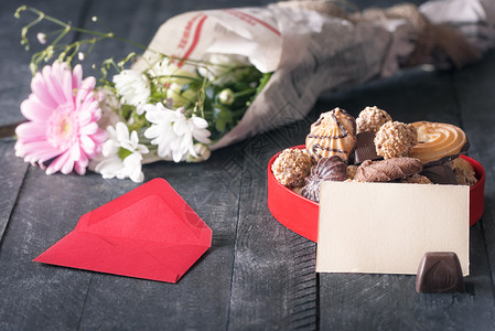 照片上有一张空白纸条贴在一盒甜食上四周都是红包和一束花图片
