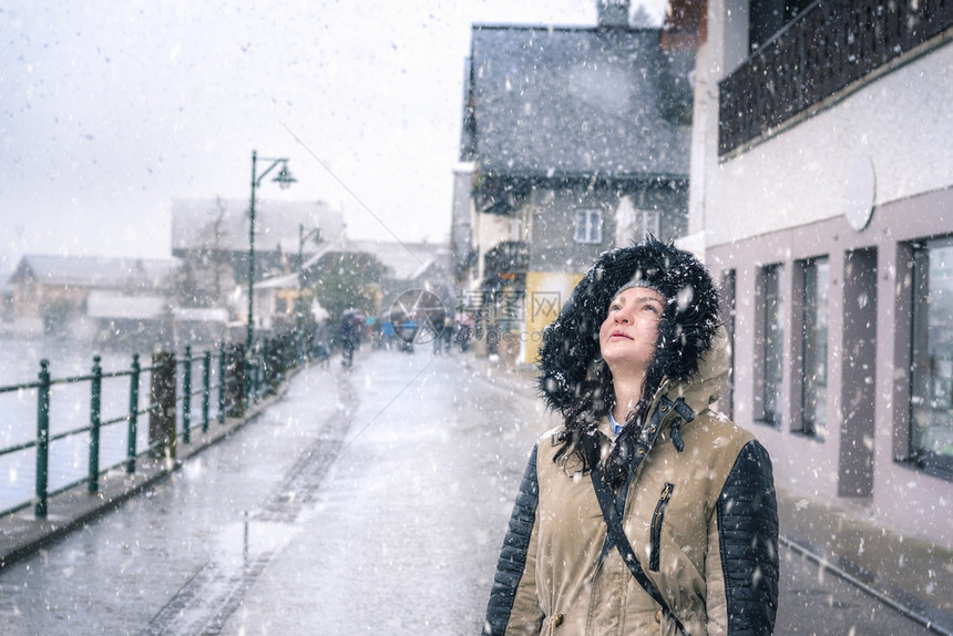 冬天美丽女孩在街道上仰望天空享受下雪图片