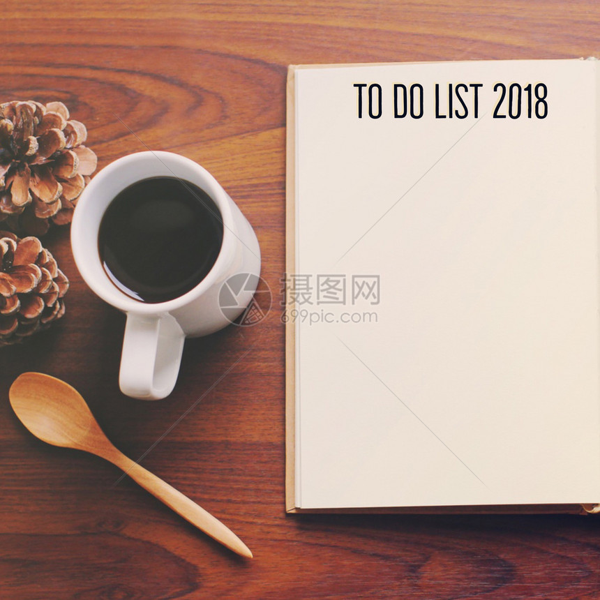 要将2018列在空白笔记本上的2018列表中在木制桌顶视图上加咖啡和勺子图片