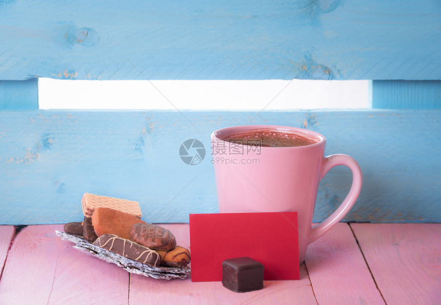 在树皮上的一堆糖果和张空白的红色纸上在粉红色的木制桌子和背景的蓝色栅栏上图片