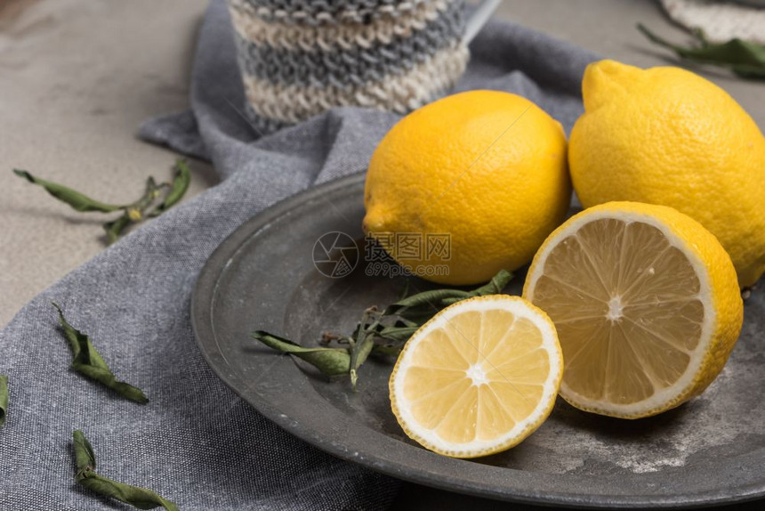 新鲜柠檬和叶在生锈盘上新鲜柑橘水果背景图片