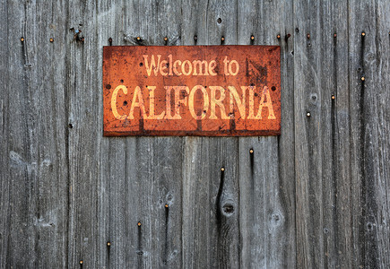 木制墙上有生锈的金属标志上面写着欢迎来到加州图片