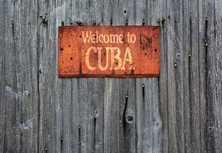 木制墙上有生锈的金属标志上面写着欢迎来到古巴图片