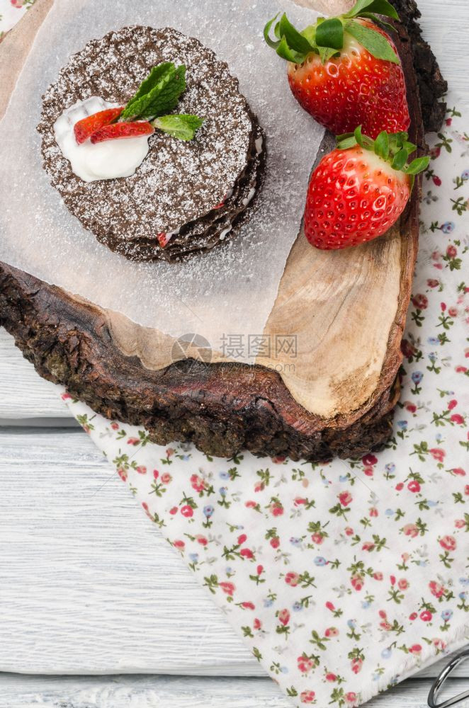 木制桌上有草莓奶油和薄叶的巧克力贝吉安华夫饼木制桌上有草莓奶油和薄片图片