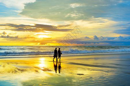 日落时在美丽海滩散步的情侣图片