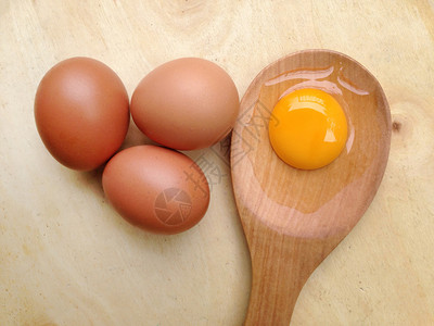 鸡蛋和木背景的勺蛋黄图片