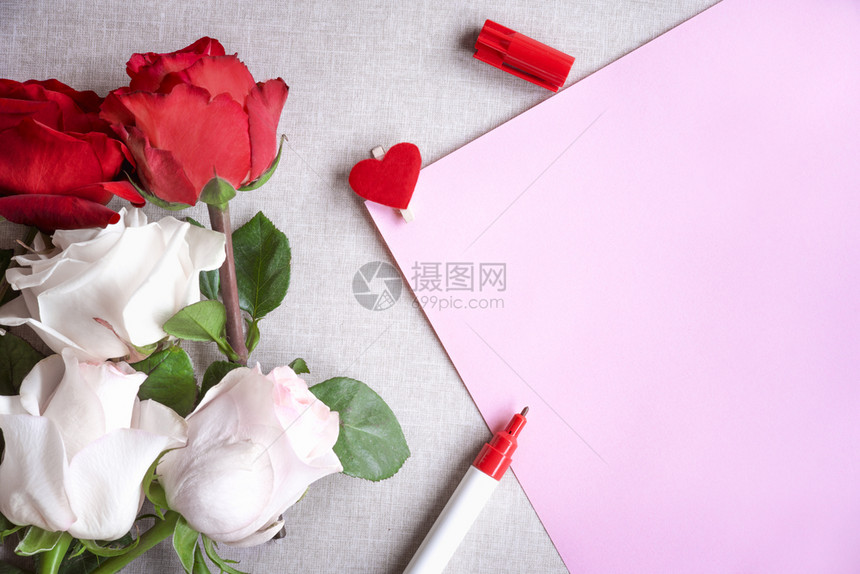 红白玫瑰和一张粉纸上面装饰着红心的木片和一支红记笔图片
