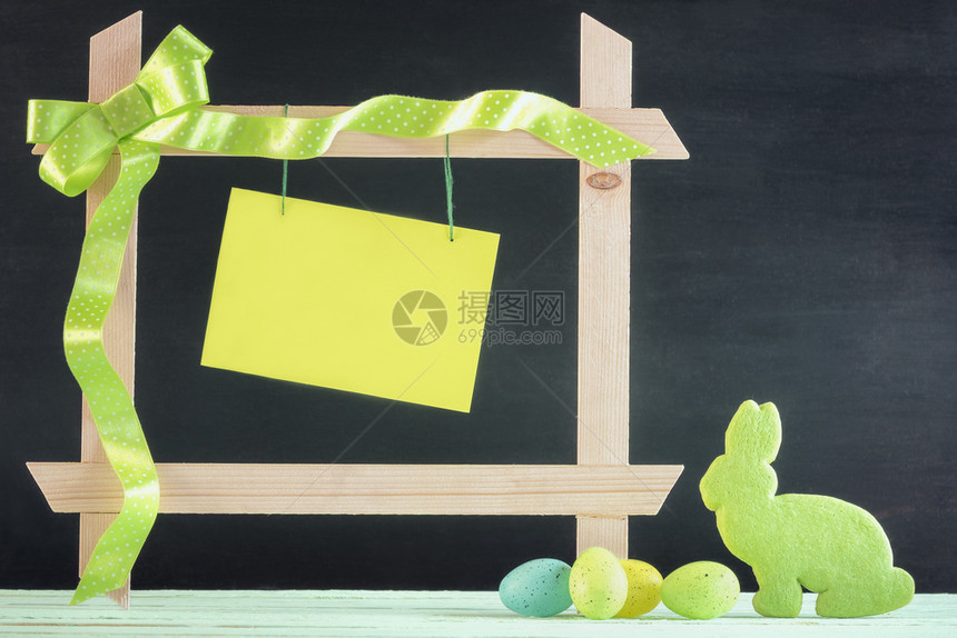 长着彩蛋的东边卡片一只兔子形状的饼干和一张带丝弓的木框以及一张黑色背景的空白绿信息卡片图片