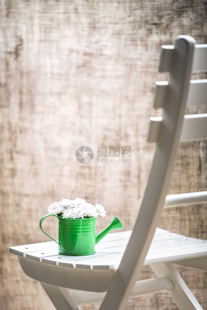 绿色水罐中的白花束放在色木椅上窗前装着黄麻帘一种生锈的风格图片
