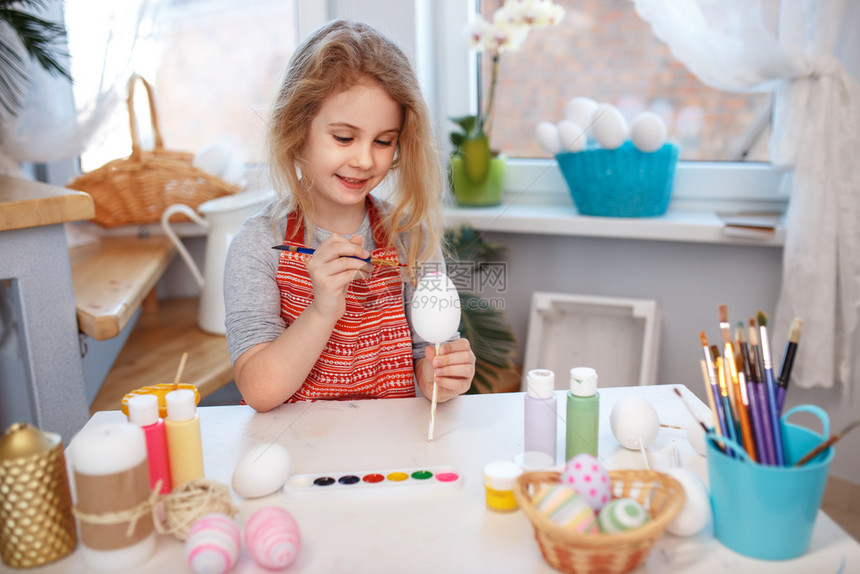 金发女孩在家里在鸡蛋上绘画图片