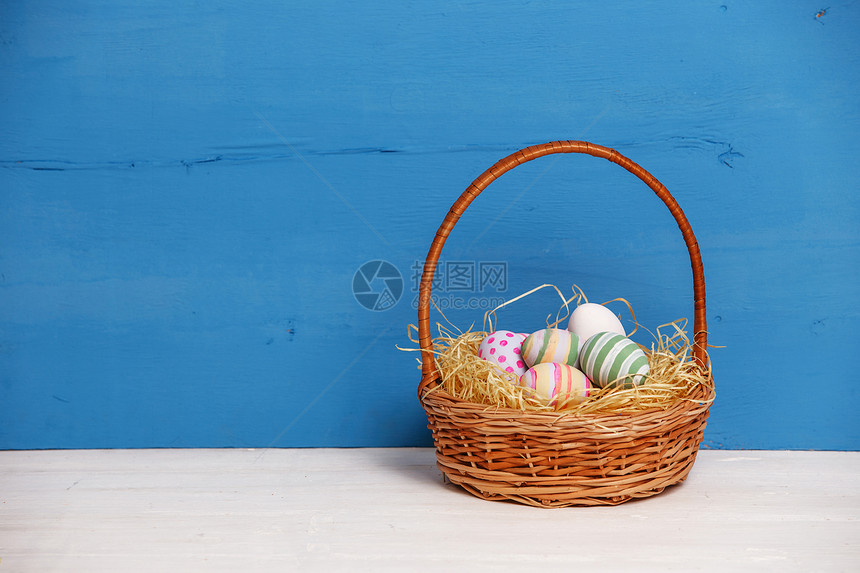 蓝底背景篮子里带条纹和斑点图案的鸡蛋图片