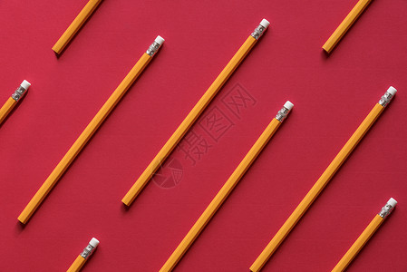教育背景概念与一堆黄木铅笔排列对称就像红色纸页上的图案图片