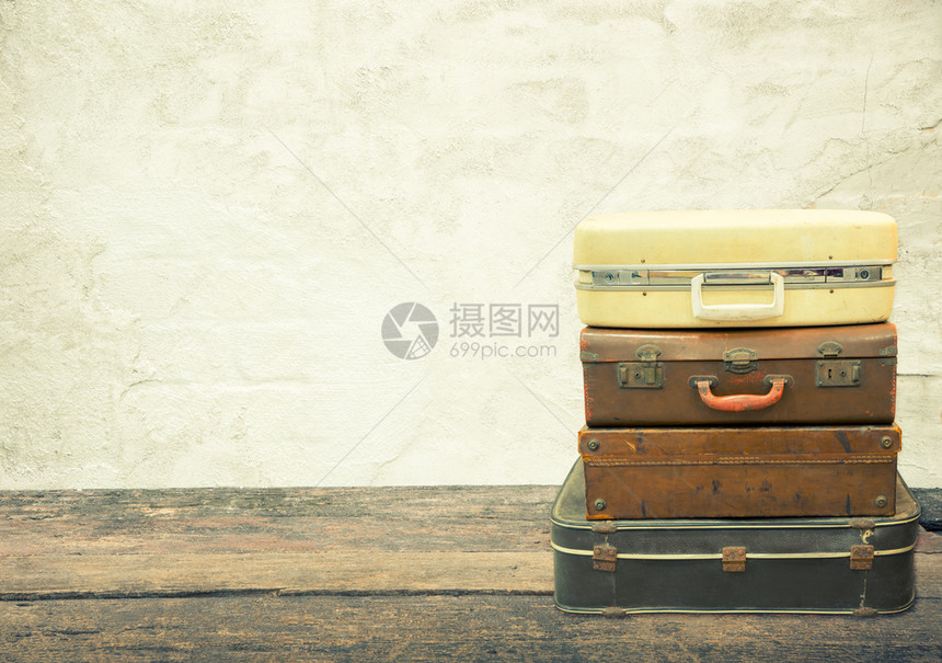 旧混凝土背景的木板上堆叠式皮革行李旅概念图片