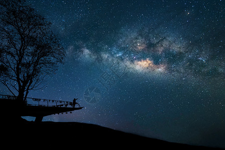 夜空多彩的有星和在山上举起双臂的快乐男士轮廓自由旅行的周末假期长图片