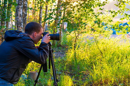 一个在三脚架上拿着相机的人拍摄自然图片图片