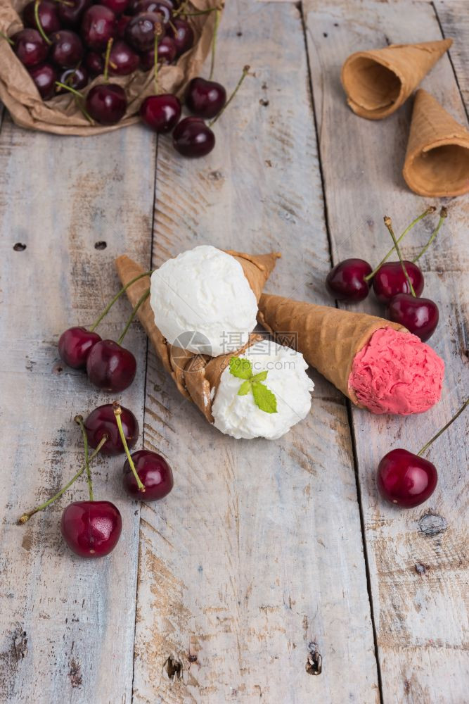 木制桌上的冰淇淋樱桃和新鲜樱桃图片