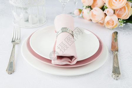 漂亮的装饰桌上面有白色和粉板眼镜银器粉色餐巾纸和豪华桌布上的鲜花图片