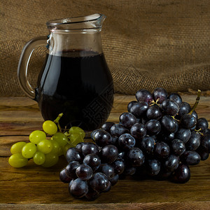 一堆葡萄和黑木本底的葡萄酒壶一堆团酒杯玻璃葡萄团图片