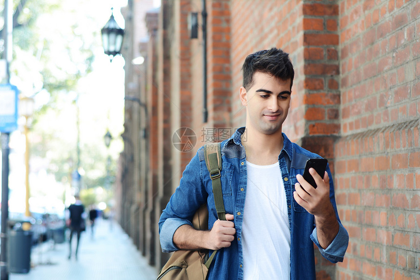年轻拉丁男子的肖像在他手机上打字户外拉丁男子在他的手机上打字图片