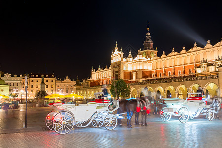 在夜晚的克拉科夫市中心以购物队列为背景的马车和马匹图片