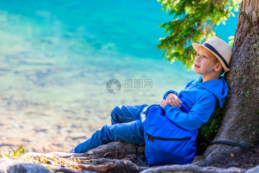 一个小学生旅行者背着背包在湖边休息图片