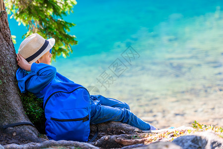 一个小学生旅行者背着背包在湖边休息图片