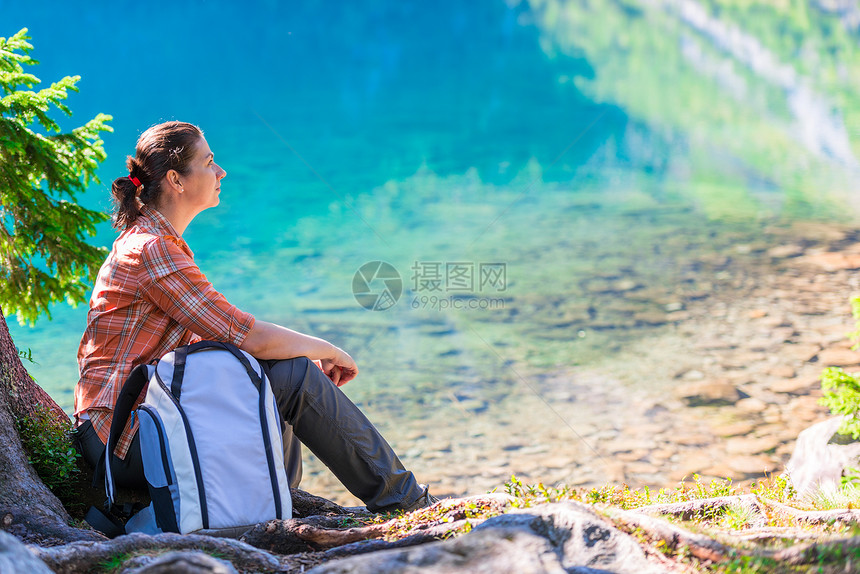 背着包的旅行者坐在湖边塔特拉山上的摩尔斯基奥科湖边背着包的旅行者坐在湖边摩尔斯基奥科湖边图片