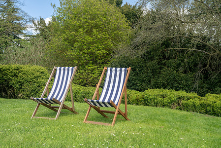 在花园草坪上两张典型的英语甲板椅夏季在英语花园中两张带有脱衣布的英国双张式甲板椅在花园草坪上两张典型的英语甲板椅背景图片
