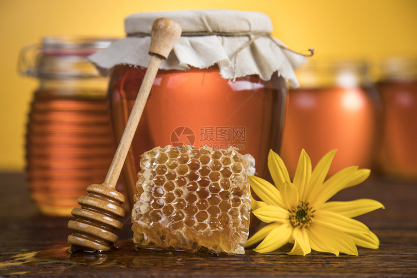 装在梳子上的甜蜂蜜装在木本底的玻璃罐图片
