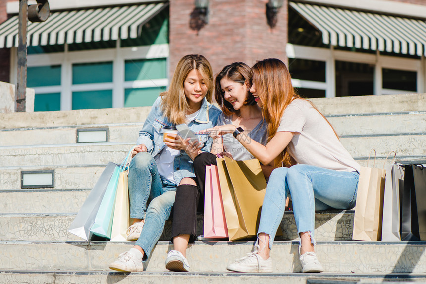 在城市购物时使用智能手机城市年轻时快乐与朋友一起自画肖像图片