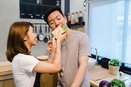 美丽的亚裔夫妇在厨房里互相喂养年轻的亚裔男女在家里有浪漫的时光图片