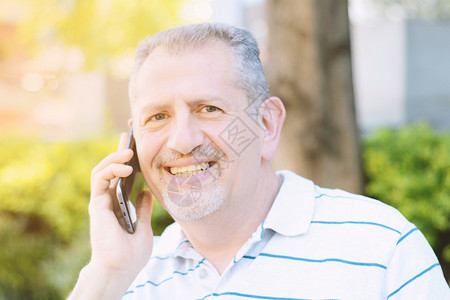 英俊的中年男子在公园户外技术概念英俊的中年男子在电话交谈图片