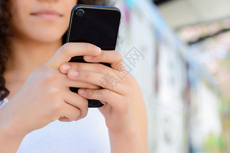 短讯服务美丽的latin年轻女在街上用智能手机发信息背景