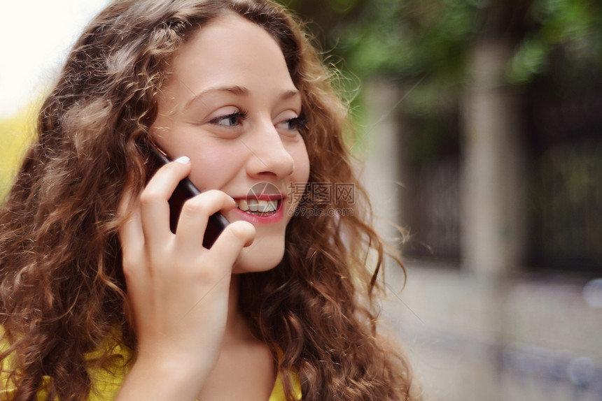 年轻拉丁女人在户外用手机聊天的肖像图片