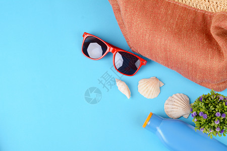 蓝色背景的太阳镜贝壳海星和防晒霜图片