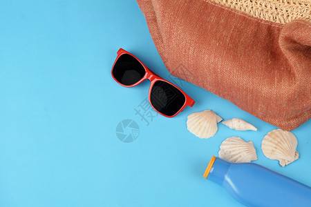蓝色背景中的太阳镜防晒霜和贝壳图片