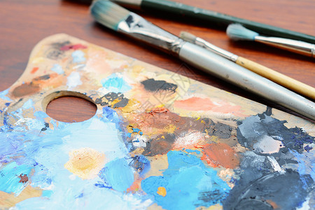 艺术家配有彩色油画笔和木背景上的油漆刷子调色板艺术概念配有彩色油画笔和漆刷子的调色板背景图片