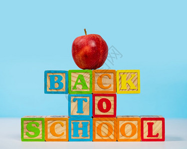 堆叠成的木块放回学校上面顶着红苹果蓝色背景回到学校用苹果木块拼写出来图片