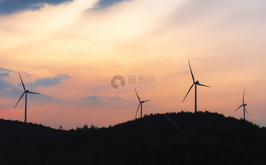 风力涡轮机发电的廓在日出落的一座木质山顶badenwurtembg地区在德国的schwabial镇附近图片