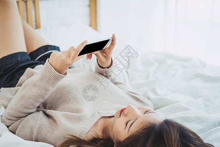 女人躺在床上看手机图片
