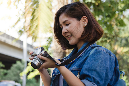 年轻快乐的亚洲女在城市巡演期间用相机拍照欢乐的情绪极好城市概念中的户外生活方式背景图片