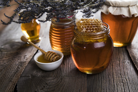 蜂蜜罐加调料和流动蜂蜜木制桌上的新鲜蜂蜜图片