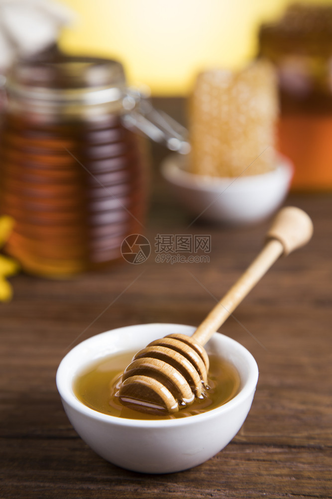 装在梳子上的甜蜂蜜装在木本底的玻璃罐图片