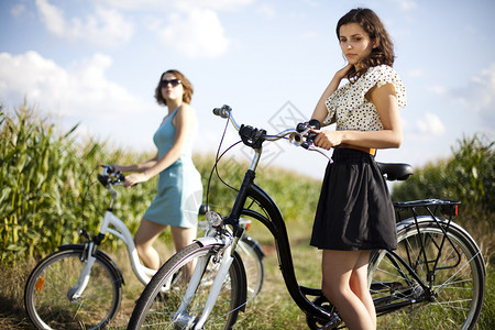两年轻女子骑着自行车在玉米地停顿图片