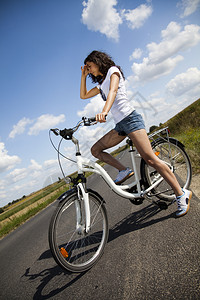 女孩骑着自行车在路上张望图片