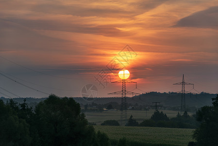 美丽的早晨红色日出在一个德国村庄和自然太阳位于高压电线杆的顶部图片